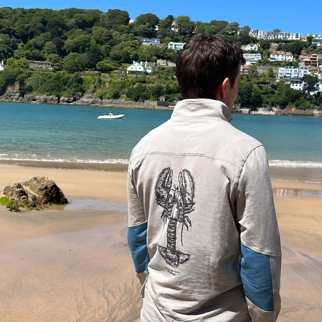 Man on beach wearing a John Aspden Graphic Sweatshirt. Limited edition lobster print in collaboration with Jellymud.